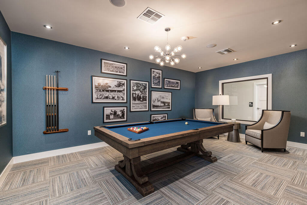 Modern clubhouse room with stylish billiard table next to a cushioned chair